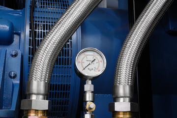 a pressure gauge is attached to a silver tube on a large diesel engine.