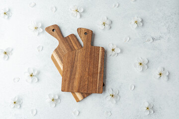 Wooden cutting boards on a light surface with delicate white flowers arranged