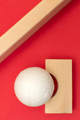 Still life with wooden blocks and a a plastic foam ball on red background
