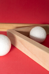 Still life with wooden blocks and a a plastic foam ball on red background