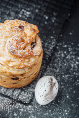 Freshly baked pastry with powdered sugar and speckled egg on black background