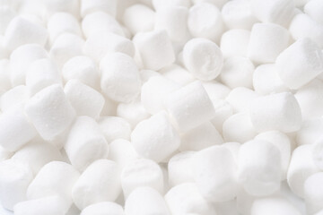 Close-up of a pile of small white marshmallows with soft texture and bright lighting. Perfect for dessert concepts, backgrounds, or seasonal treats.