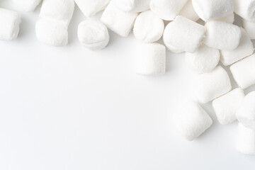 Top view of mini white marshmallows scattered on a clean white background, ideal for sweet treats, desserts, or holiday themes.