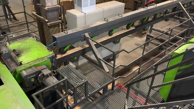 Wooden plank moving along conveyor belt within industrial sawmill, demonstrating automated wood processing and transportation through advanced machinery