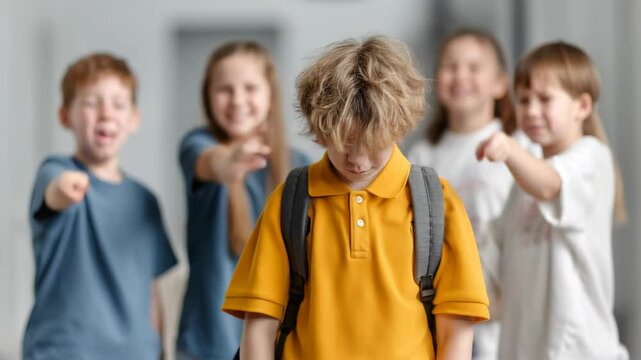 Sad schoolboy being bullied by classmates pointing fingers at him