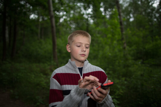 boy in the forest dials a number on a smartphone