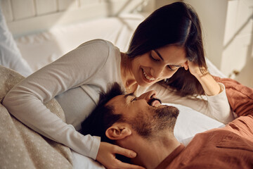 Young affectionate couple talking in bedroom.