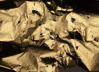 Golden metallic foil with crumpled, torn texture. Shiny, bright surface with wrinkled, jagged edges...