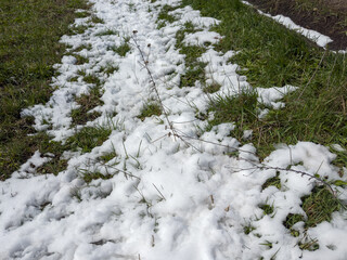 Field with grass and remains of melting freshly fallen snow