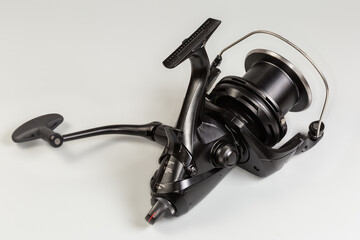 Modern fishing reel for recreational fishing on a gray background