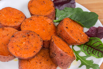 Baked sweet potato tuber sliced into circles on dish