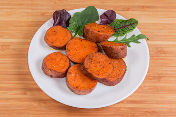 Baked sweet potato tuber sliced into circles on dish