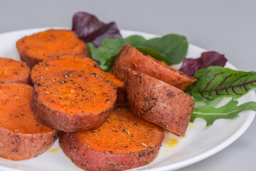 Baked sweet potato tuber sliced into circles on dish