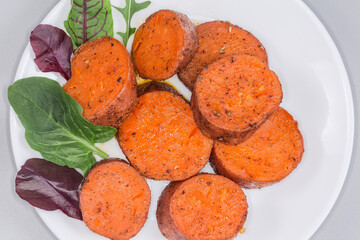 Baked sweet potato tuber sliced into circles on dish