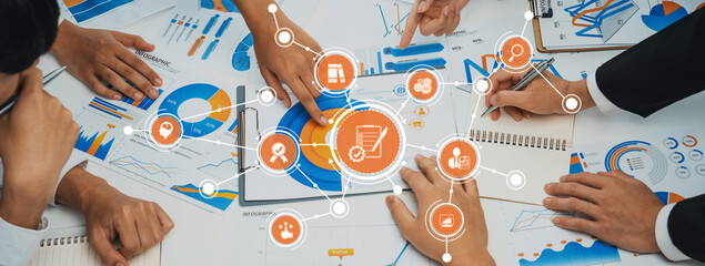 Engaging business strategy session with diverse team analyzing charts and graphs on a table, fostering collaboration and effective communication for informed decisions. Amity