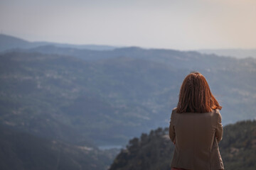 Mulher de costas a olhar para o horizonte nas montanhas