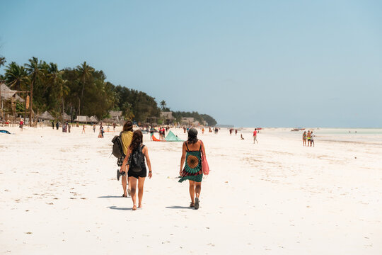 Tourists walking on sunny paje beach in zanzibar, tanzania