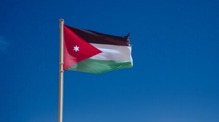 Jordanian flag waving on a clear sunny day against blue sky