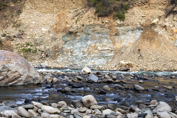mountainous rocky river bed with small stream from flat angle