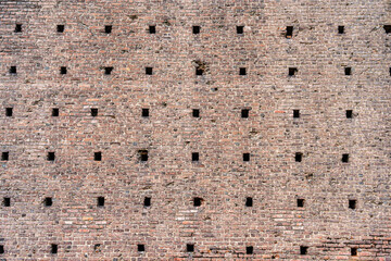 A close-up view with the medieval brick wall part of the historic Sforza Castle (Castello Sforzesco) in Milan, Italy. Brick wall background texture.
