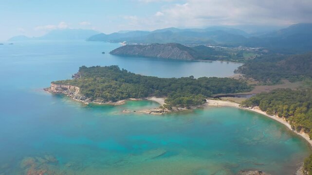 Breathtaking drone shot of the fascinating Phaselis Bay and ancient city in the Kemer region. Lush nature surrounded by turquoise waters.