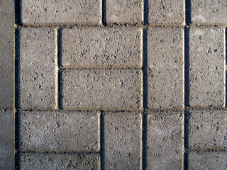 A sidewalk made of gray bricks with potholes. The bricks are neatly laid out in different directions. Rhythmic geometric stone background. Copy space.