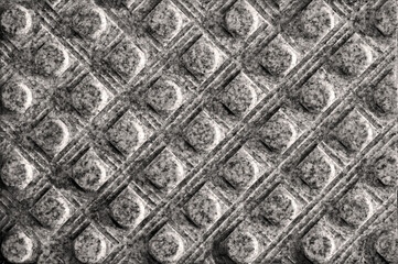 Texture of tactile granite tiles with a grooved surface. Lines of squares, with cylinders in the center, are arranged rhythmically along the diagonal. Stone paving slabs background.