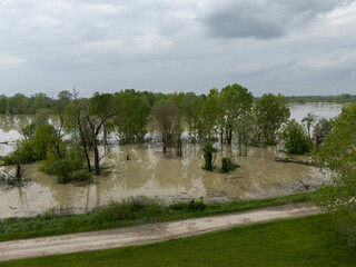Flooding landscape around dirt road, Po River waters inundating trees and farmland in Emilia Romagna after intense rainfall