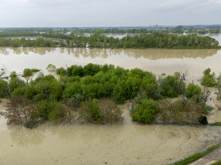 Floodwaters from Po River engulfing agricultural landscape near Olza, Emilia Romagna, drowning fields, trees, vegetation in muddy, desolate scene