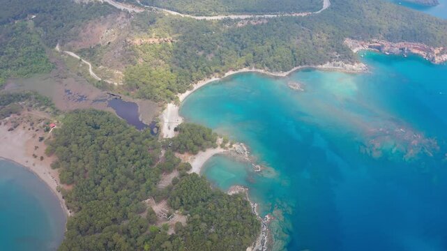 Impressive drone view of Phaselis Bay and its surroundings. Turquoise colored waters, lush green forests and traces of the ancient city spreading along the coastline, exhibit a unique harmony.
