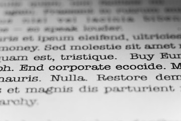End corporate ecocide. Text printed on a page. A piece of paper with a phrase written in retro...