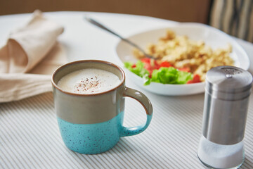 Breakfast table. Cup of coffee and plate with scrambled eggs and vegetables on the table