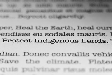 Fototapeta premium Protect indigenous lands. Text printed on a page. A piece of paper with a phrase written in retro typewriter font.