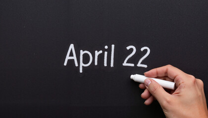 Hand writing "April 22" on chalkboard