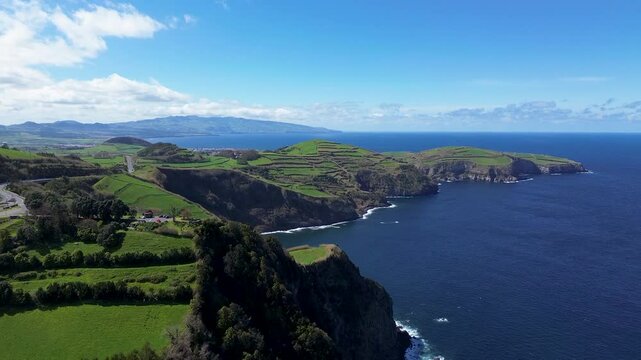 Drone footage captures the dramatic coastal cliffs and terraced farmland of S&atilde;o Miguel, Azores, likely near Ponta do Cintr&atilde;o, where lush green fields meet the vast Atlantic Ocean