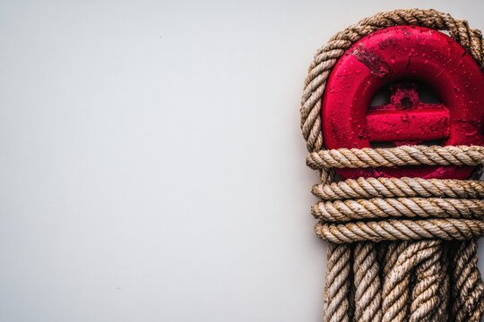 Red mooring cleat and rope on white background; nautical detail