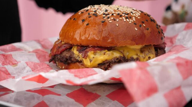 Unwrapping big juicy burger with meat and vegetables and sauce closeup