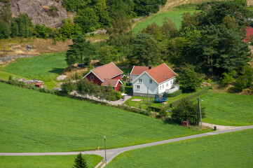 Aerial view of red-roofed house in green valley.