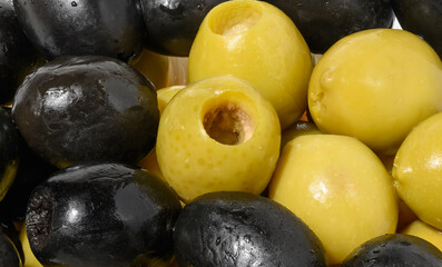 Detailed close up mix of smooth, pitted green and black olives, filling the frame