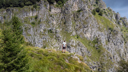 Man alone seen from behind admiring nature. Boy hiking in the mountains admiring the beauty of...
