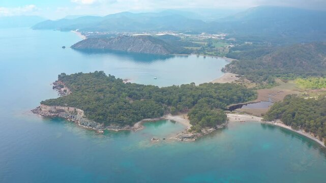 Phaselis Bay, turquoise waters, lush forests and the ruins of the ancient city scattered along the coastline become more apparent as the drone slowly approaches.