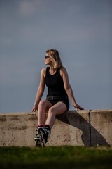 Blonde girl sitting and relaxing in a sunny day after rollerblade skating for fitness