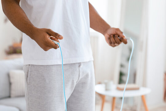 Unrecognizable Black Man Holding Jumping Rope Exercising Training In The Morning Standing At Home. Sporty Lifestyle, Physical Workout Routine With Jump Rope Concept. Cropped