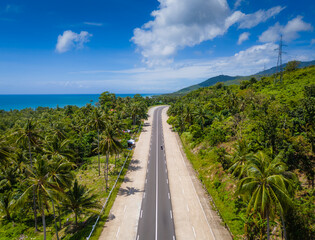 Exotic palm tree road to El Nido at Palawan island, Philippines. Aerial drone photo. Open road trip from Puerto Princesa to El Nido 
