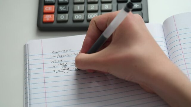 A student doing math in a notebook. Close up.