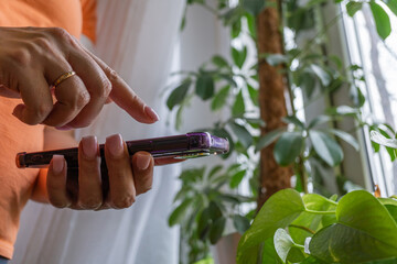 Caucasian female using smartphone indoors surrounded by lush green plants