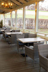 Cozy outdoor caf? seating with wicker chairs and chandelier in bright daylight