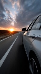 A silver car drives on a highway at sunset.  A view from inside the car