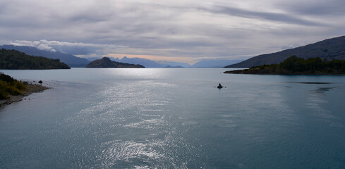 Sunset on a lake. Fishing boat at sunset in Patagonia, Chile. Beautiful summer landscape. Calm windless weather, heavy clouds.