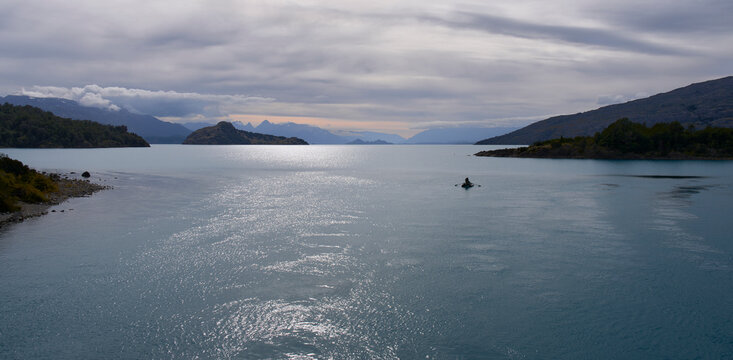 Sunset on a lake. Fishing boat at sunset in Patagonia, Chile. Beautiful summer landscape. Calm windless weather, heavy clouds.